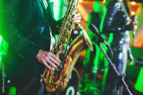 Canvas Print Concert view of a saxophone player with vocalist and musical jazz band in the ba