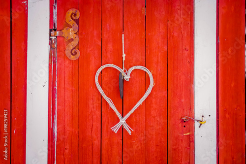 Close up of heart made of branches hanging in from a red door in a winter season in Norway photo