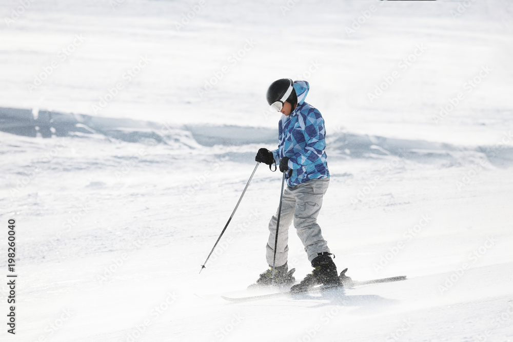 Man skiing on snowy piste at resort. Winter vacation