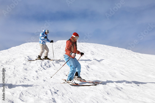 Tourists on ski piste at snowy resort. Winter vacation
