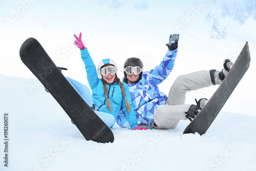 Couple of snowboarders on ski piste at snowy resort. Winter vacation