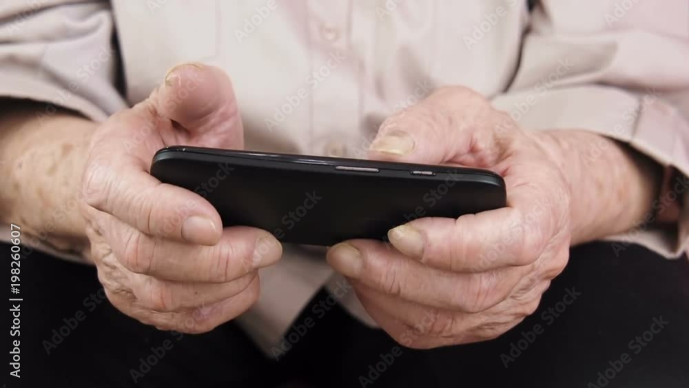 Elderly with a gadget. Hands of the elderly with a phone. Elderly with a gadget. Hands of the elderly with a phone.