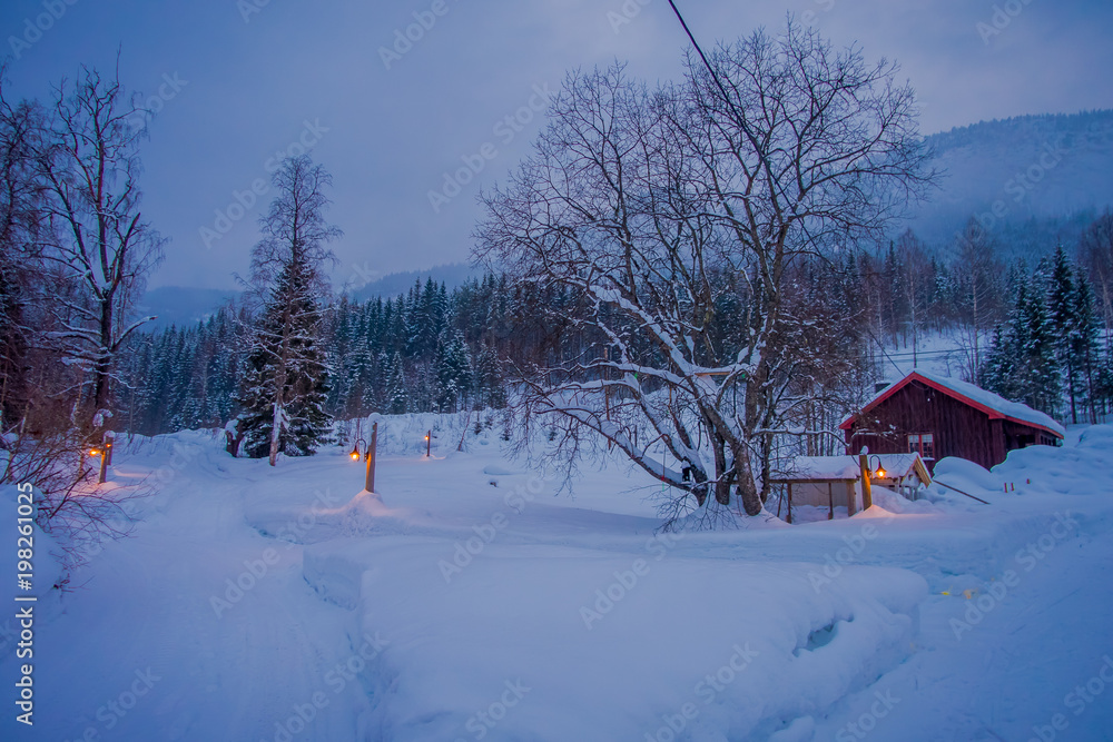 Amazing night view of traditional wooden houses with snow in the roof in stunning nature background, with some lights and posts at outdoors in Valdres region in Norway