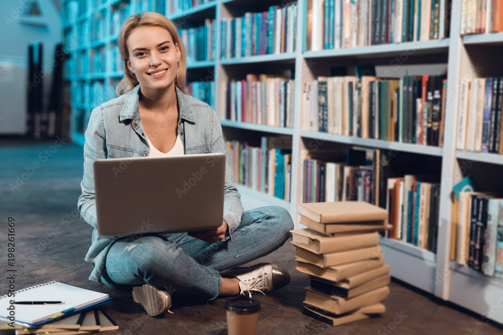 White girl near bookshelf in library. Student is using laptop. White girl near bookshelf in library. Student is using laptop.