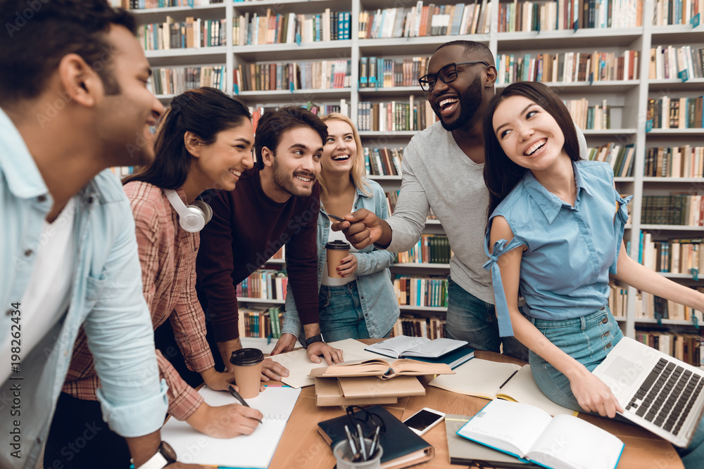 Group of ethnic multicultural students talking and laughing in library. Group of ethnic multicultural students talking and laughing in library.