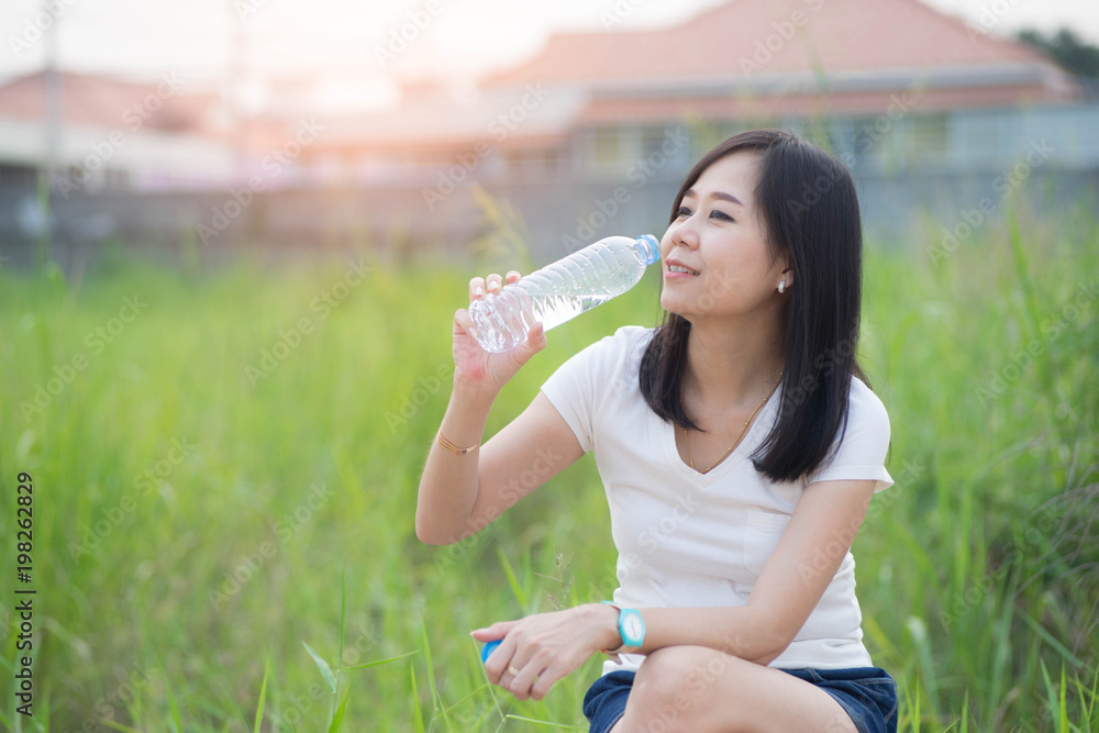 Healthy asian woman holding water bottle on green nature background. Healthy asian woman holding water bottle on green nature background.