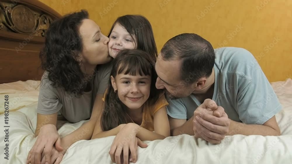 Family is playing in the bedroom. Portrait of a happy family. The parents with the children lie on the bed. Family is playing in the bedroom. Portrait of a happy family. The parents with the children lie on the bed.