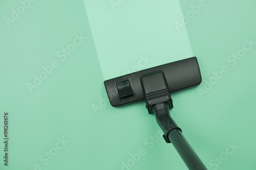 Vacuum cleaner cleaning on the green floor background showing house cleaning concept.