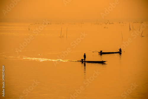 Silhouette fishermen on boat on river driving to fish © goldquest