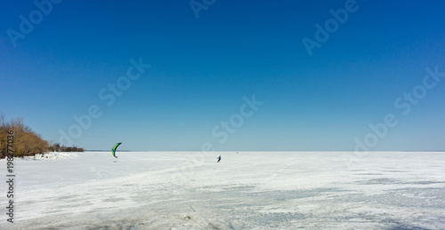 Kite surfer on skis on a frozen lake.