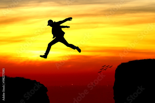 Silhouette of a man jumping over the cliff
