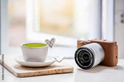 cup of green tea and classic camera on white table