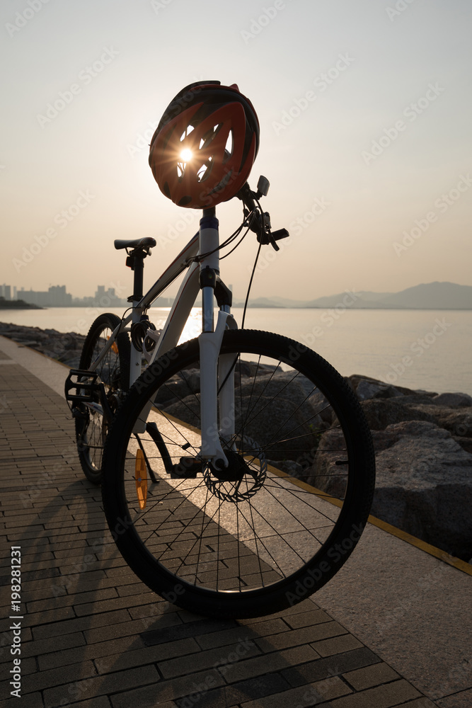 Fototapeta premium mountain bike with helmet on sunrise coast