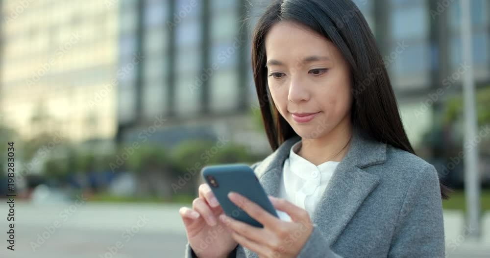 Asian Businesswoman look at mobile phone at city in the evening Asian Businesswoman look at mobile phone at city in the evening