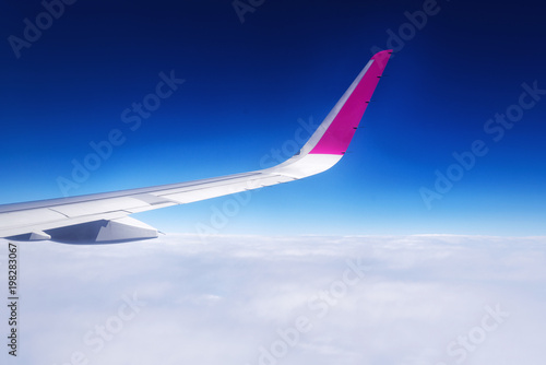 Travel concept. Wing of airplane flying above the clouds in the sky. Copy space