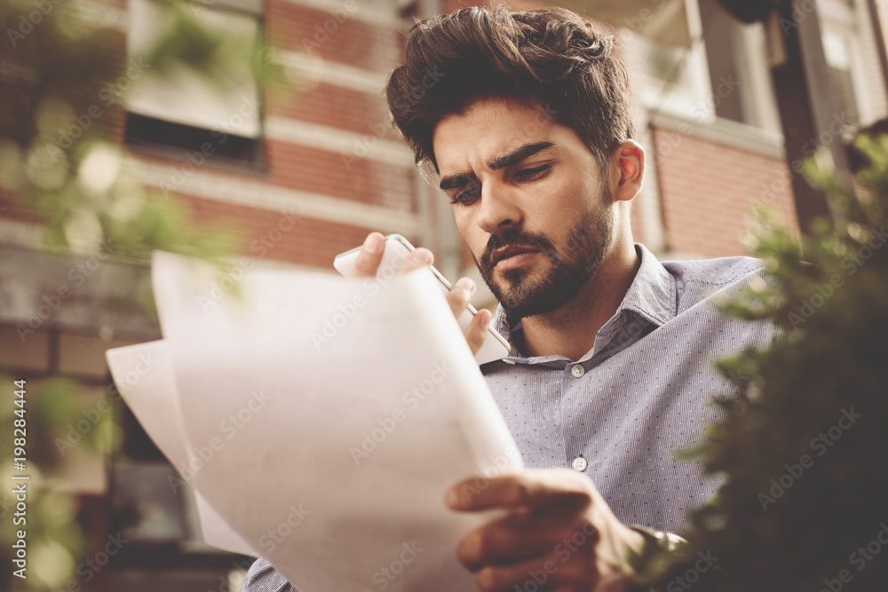 Serious businessman in outside reading document. Serious businessman in outside reading document.