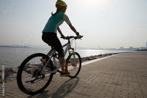 female cyclist riding mountain bike on seaside