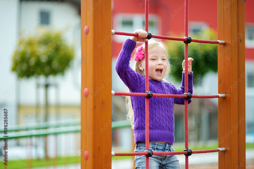 Obraz premium Cute little girl having fun on a playground outdoors in summer.