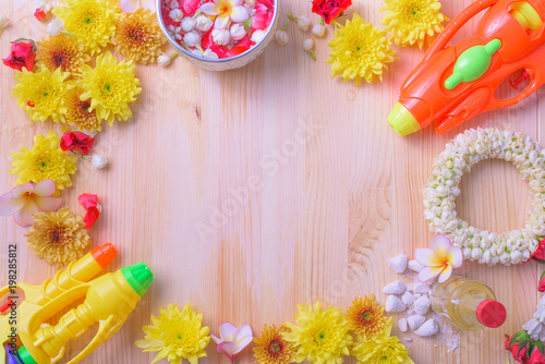 Thai traditional jasmine garland and Colorful flower in water bowls decorating and scented water, perfume, marly limestone, pipe gun on wood background for Songkran Festival or Thai New Year