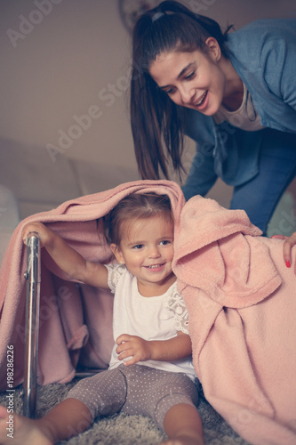 Mother and daughter playing with blanket on floor.