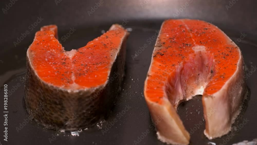 slices of red fish fried in a pan slices of red fish fried in a pan