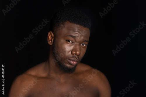 portrait of handsome young bare chested african american man looking at camera isolated on black