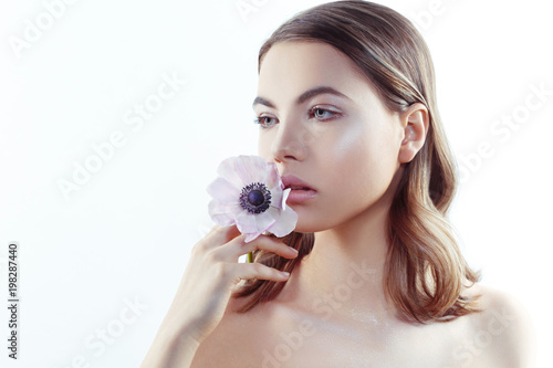 Beauty portrait of a cute girl with pink anemone flower in hands isolated on white background.