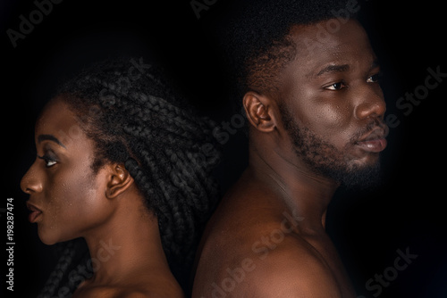 young african american couple with water drops on faces looking away isolated on black photo