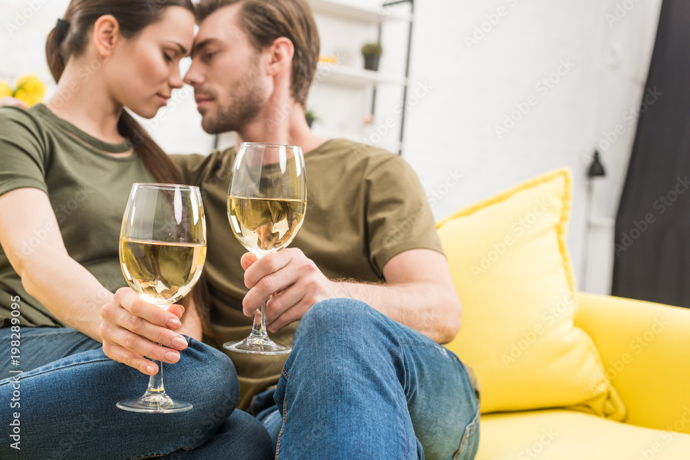 cuddling couple drinking wine together on couch at home cuddling couple drinking wine together on couch at home