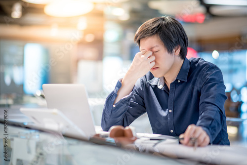Fotografie Young Asian business man feeling stressed and frustrated while working with laptop computer