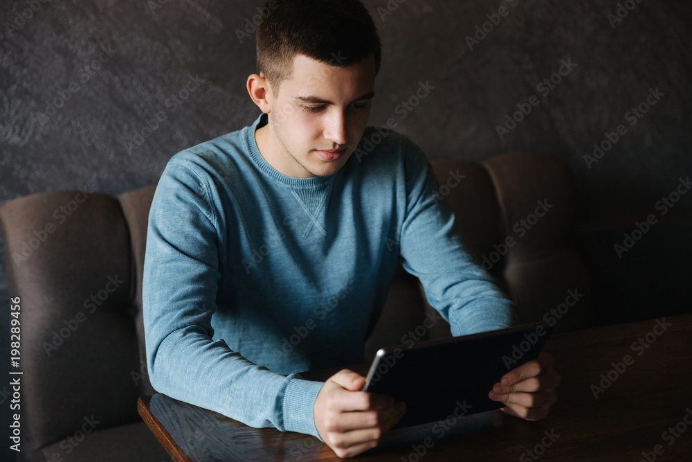 Man is sitting in a cafe and uses a tablet Man is sitting in a cafe and uses a tablet