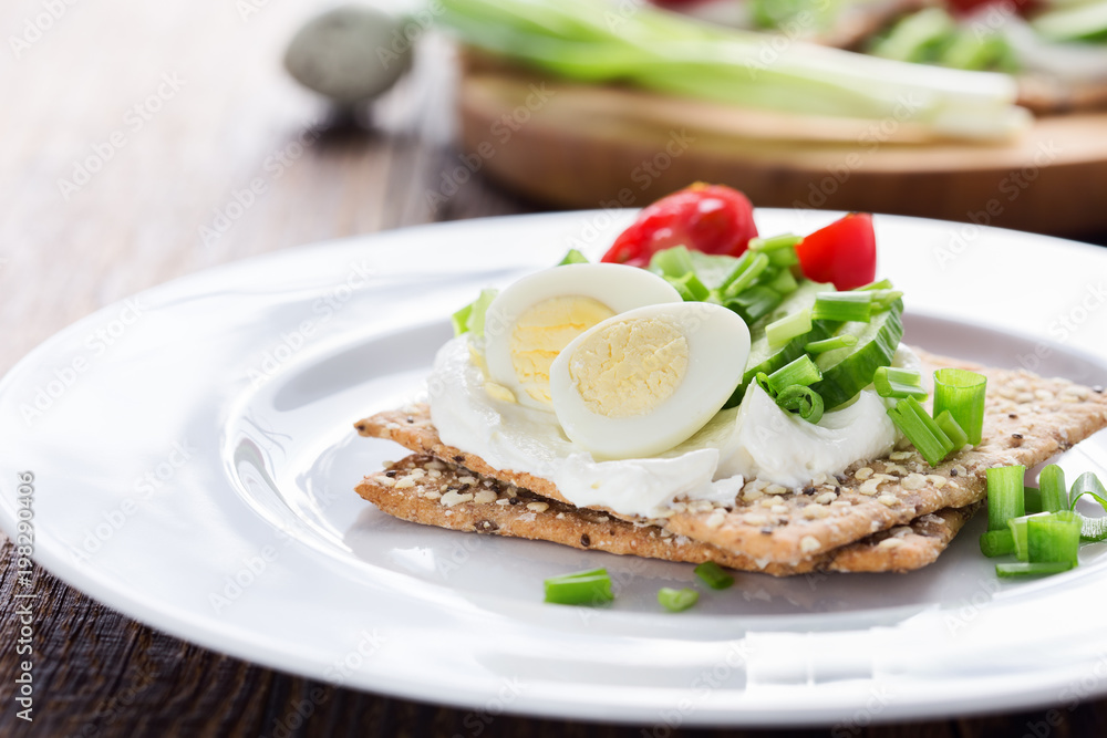 Chia seed crackers with cream cheese, cucumbers, tomato, quail egg and green onion