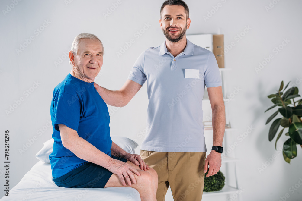 portrait of rehabilitation therapist and smiling senior man on massage table portrait of rehabilitation therapist and smiling senior man on massage table