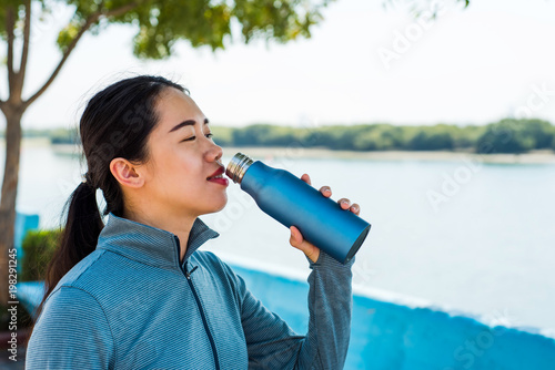 Tablou pe pânză Female hydrating after workout in the park