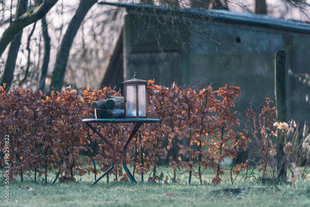 Old rusty lantern on garden table in winter. Old rusty lantern on garden table in winter.