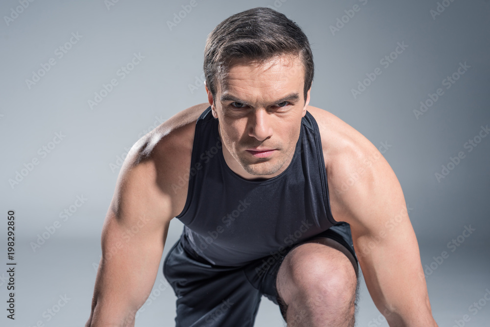 Confident sportsman getting ready for work out on grey background Confident sportsman getting ready for work out on grey background