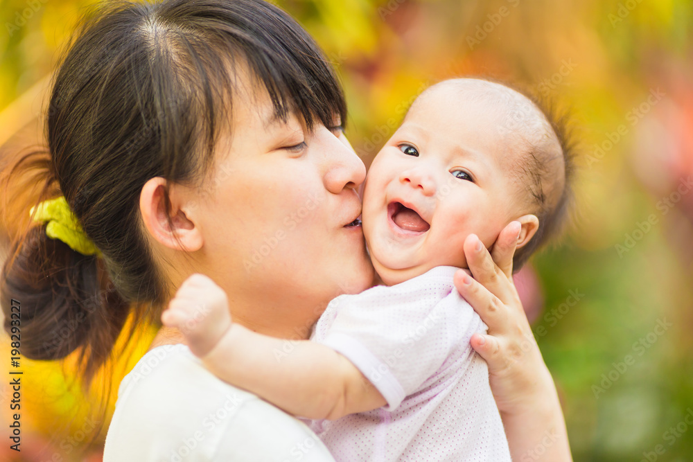 At the evening time before the sunset, 4 months baby feeling happy and smiles with her mother in the garden. At the evening time before the sunset, 4 months baby feeling happy and smiles with her mother in the garden.