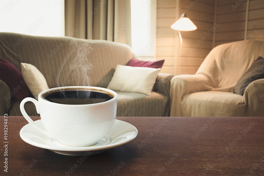 Fototapeta premium Hot coffee on tabletop in modern living room in rustic style with chair, soft divan.