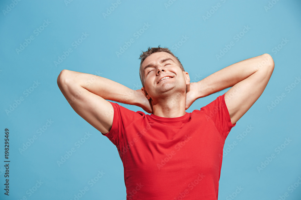 The happy business man standing and smiling against blue background. The happy business man standing and smiling against blue background.