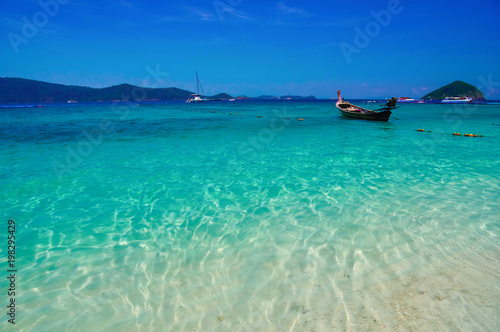 Sea bay with turquoise water and fishing boats under bright sky. Landscape blue sky and clear sea, background, copy space.