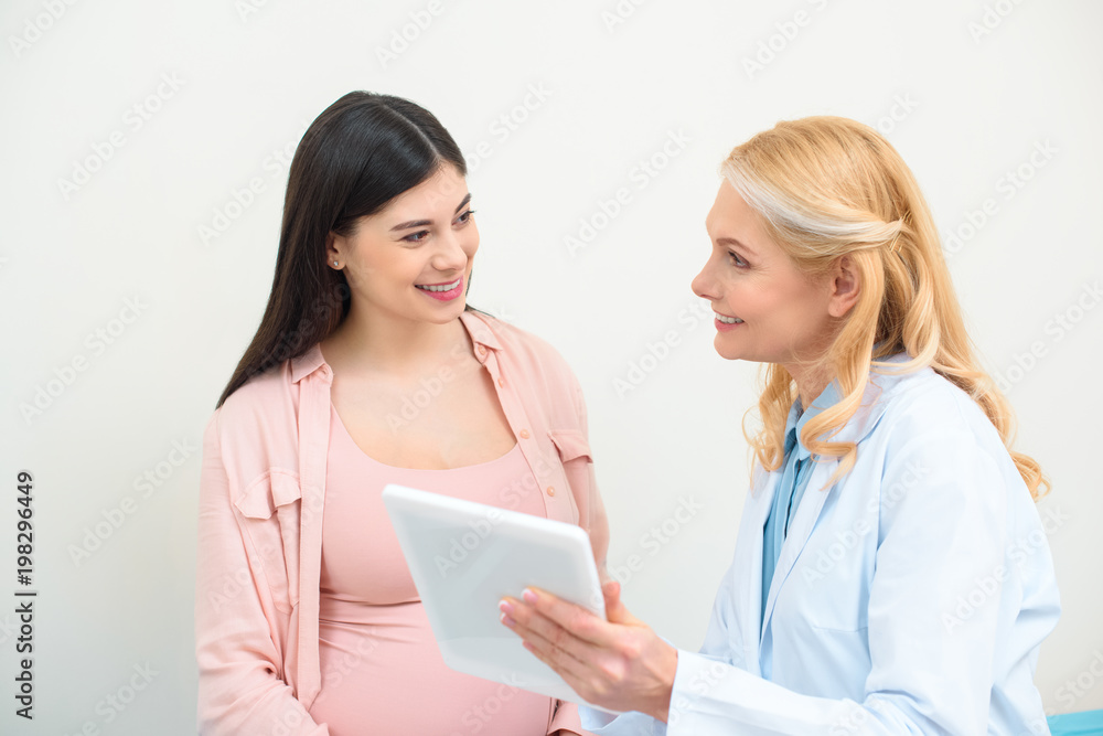 mature obstetrician gynecologist and pregnant woman using tablet together mature obstetrician gynecologist and pregnant woman using tablet together