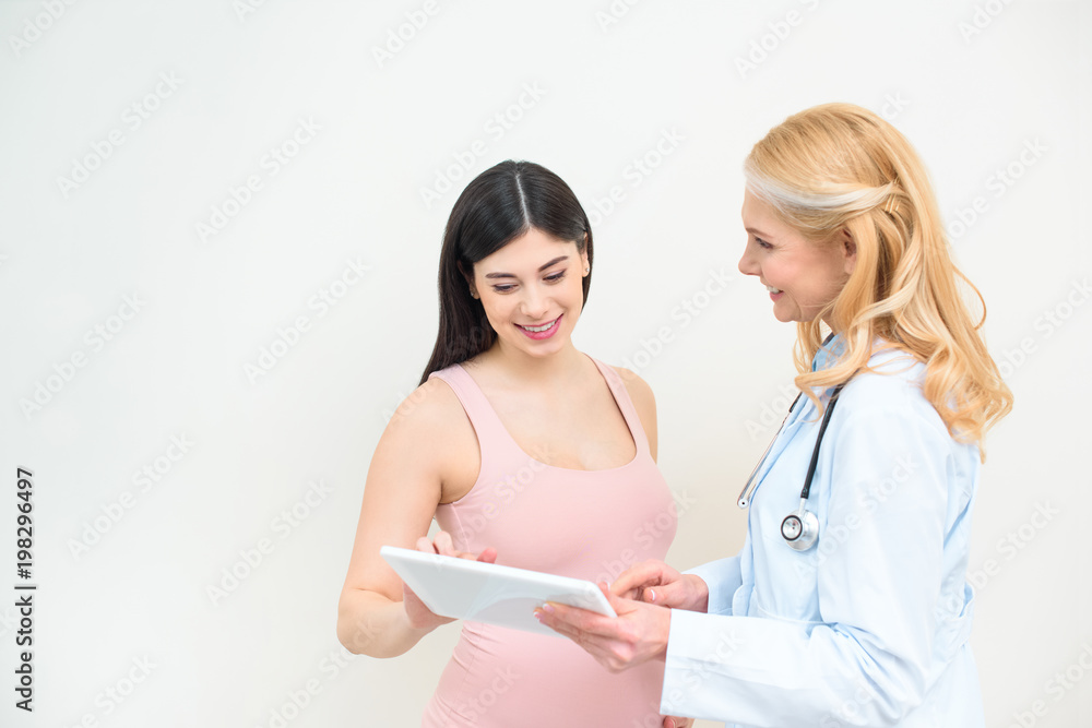 smiling obstetrician gynecologist and pregnant woman using tablet together smiling obstetrician gynecologist and pregnant woman using tablet together