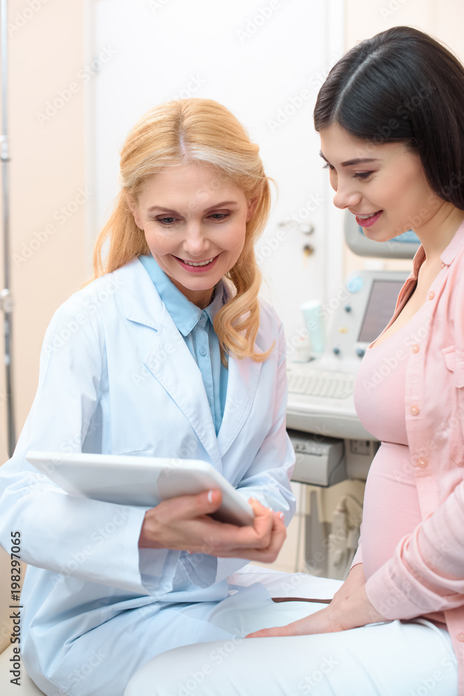 obstetrician gynecologist and pregnant woman using tablet together obstetrician gynecologist and pregnant woman using tablet together