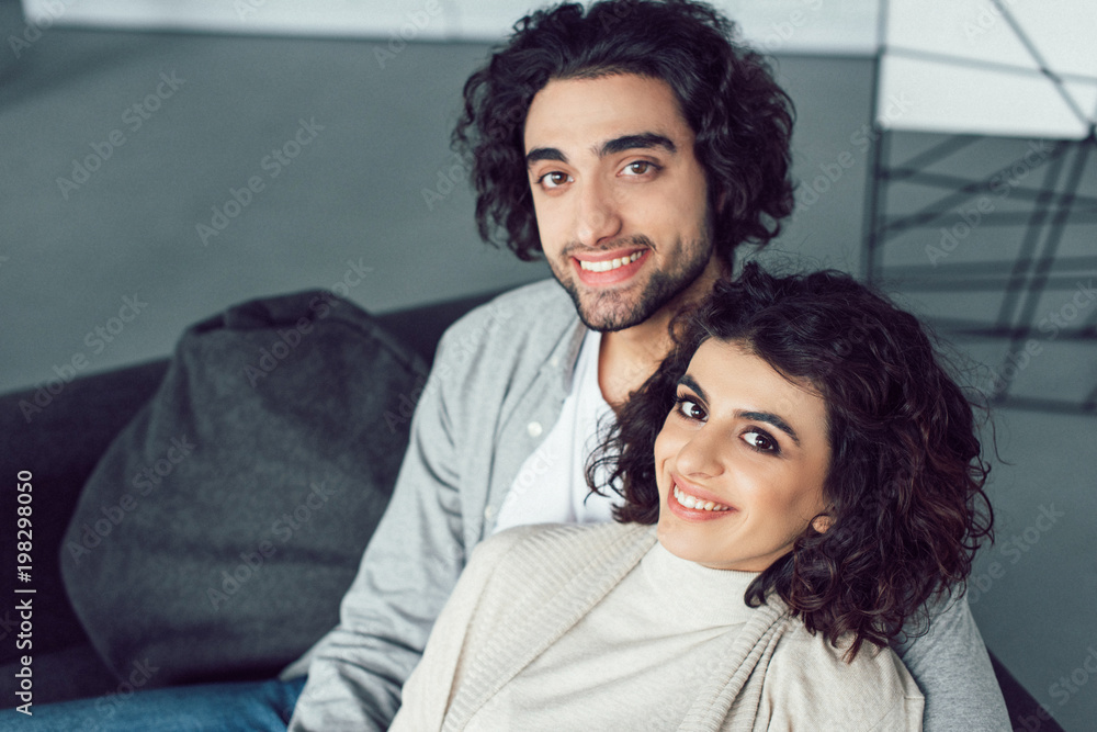 portrait of smiling young couple looking at camera at home