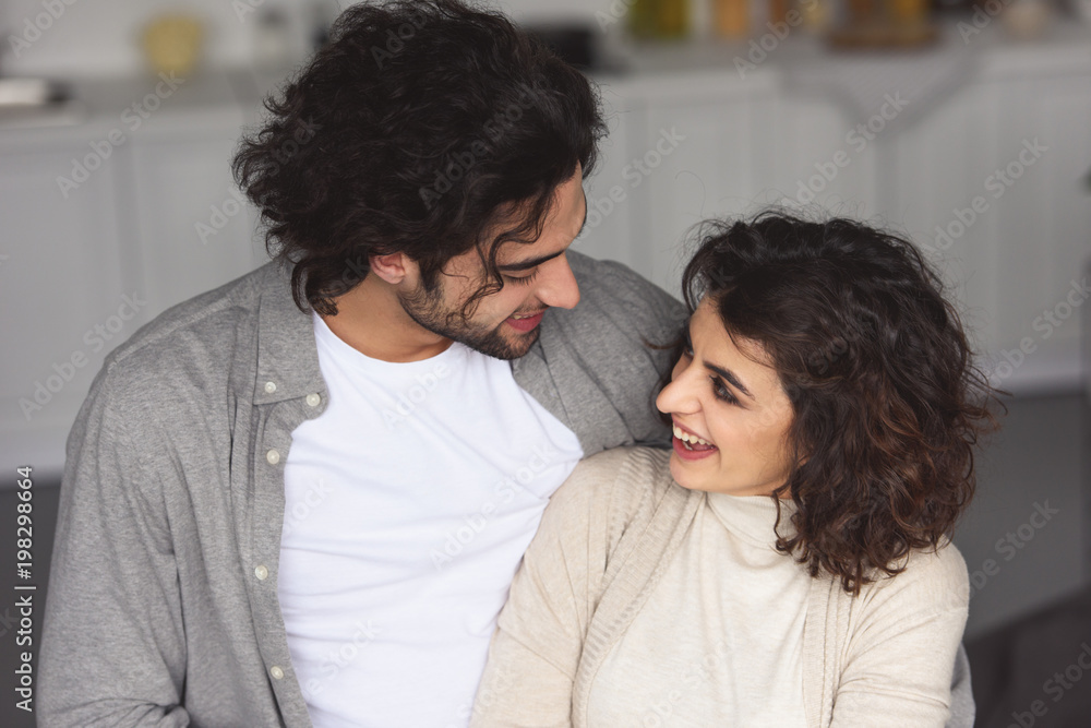 smiling young couple hugging at home and looking at each other