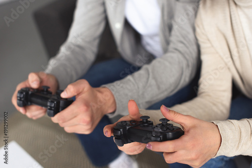 cropped image of young couple holding gamepads at home