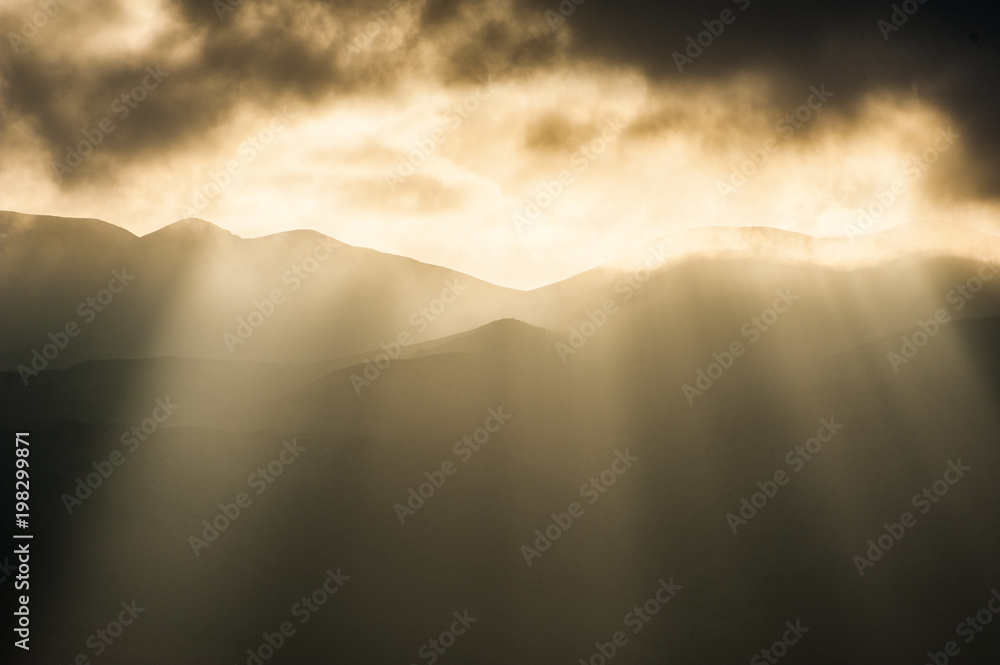 Amazing sunset sunrise with magical sunbeams and low clouds over the hills of Reserva Nacional La Chimba Amazing sunset sunrise with magical sunbeams and low clouds over the hills of Reserva Nacional La Chimba