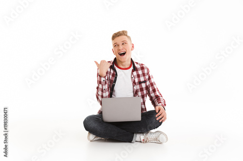 Excited young guy using laptop computer pointing to copyspace. © Drobot Dean