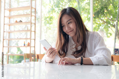 Closeup image of a beautiful Asian woman holding , using and looking at smart phone with feeling happy Free Download Closeup image of a beautiful Asian woman holding , using and looking at smart phone with feeling happy - GFXLoad