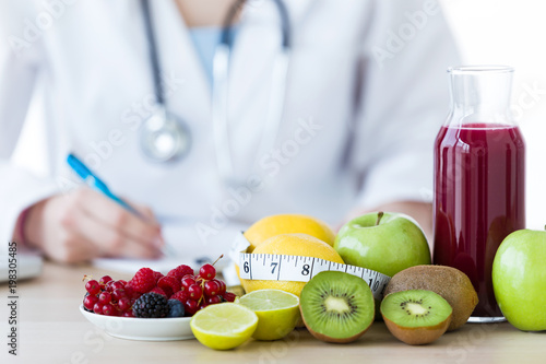 Some fruits such as apples, kiwis, lemons and berries on nutritionist table.
